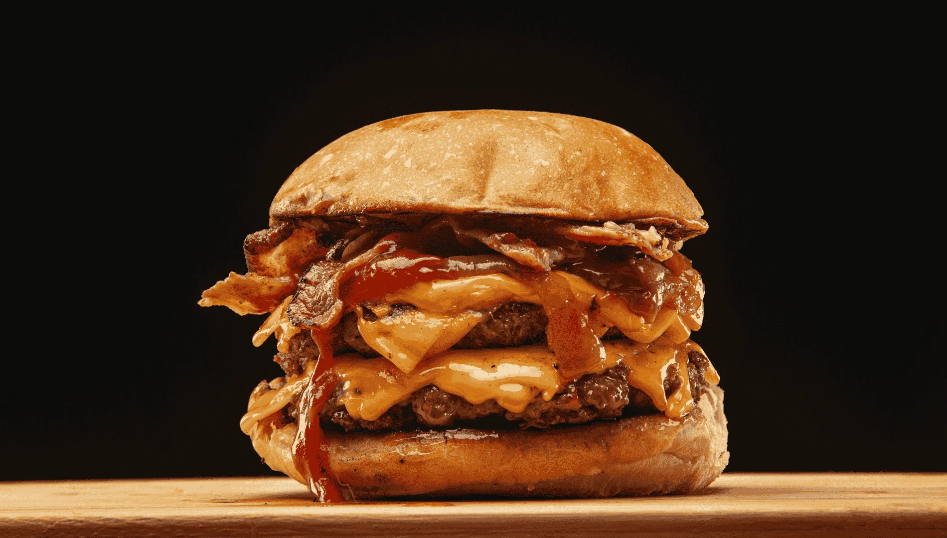 Saftige Burger Patties in einem Burger auf einem Holzbrett mit schwarzem Hintergrund